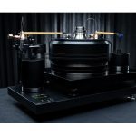J.Sikora Turntables standard line Max Hi End turntable from J.Sikora, the standard line Max is a hi end turntable with the highest manufacturing specifications. The total weight of the turntable reaches 83 kg with the platter alone being 18 kg. The platter is made of Delrin® and cast iron. The turntable uses materials such as aluminum, brass, copper, inox and bronze. The bearing is inverted with a ceramic ball. The turntable uses 2 DC motors and a rubber belt with one arm (+1 optional). It comes with a heavy-duty clamp, glass mat, with two arbors to accommodate two arms and has a high quality and precision external power supply while it is available in black or silver.